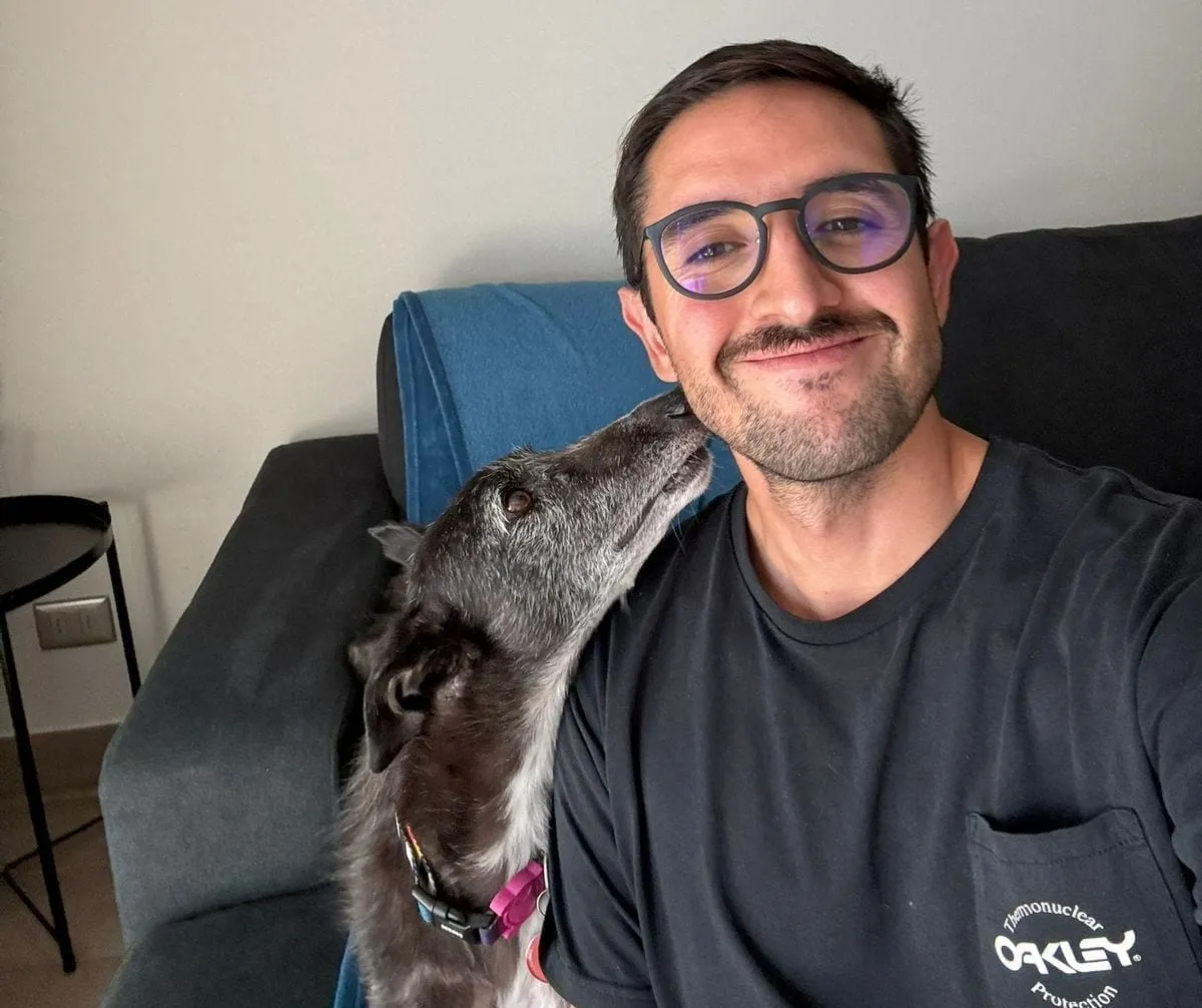 Mora, perra negra con canas, besando a una persona en un sofá.